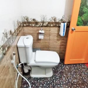 a toilet in a bathroom with an orange door at Green cottage Ella in Ella