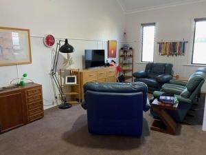 a living room with a couch and chairs and a tv at Nambucca Lodge in Nambucca Heads