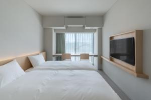 西条市にあるITOMACHI HOTEL0のベッド2台、薄型テレビが備わるホテルルームです。
