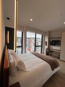 1 dormitorio con 1 cama blanca grande y ventanas grandes en Apartamento de Lujo en Quito, en Quito