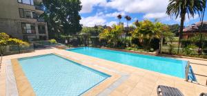 a large swimming pool in a yard with a building at Penthouse with Private Terrace, Parking + 2 Pools in Sydney