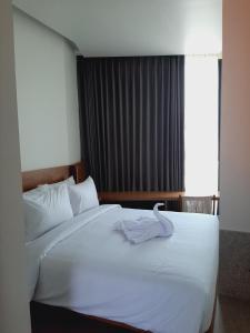 a bedroom with a white bed with a towel on it at The Fields Hotel and Apartment in Seminyak