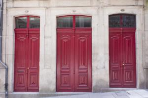 three red doors on the side of a building at Being Porto Hostel in Porto