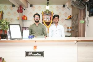 twee mannen achter een toonbank in een winkel bij Hotel Neelkiran in Navi Mumbai