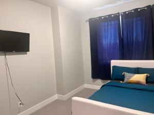 1 dormitorio con 1 cama azul y TV de pantalla plana en Private room in Calgary*Netflix*TV*Wifi*Parking, en Calgary