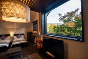 a room with a large window and a bed and a television at ユニテ蔵王ジョーニダ リゾート in Yamagata