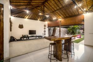 Villa Baik Baik by BaliSuperHost في سمينياك: مطبخ في الهواء الطلق مع بار خشبي مع الكراسي