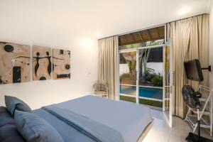 Villa Baik Baik by BaliSuperHost في سمينياك: غرفة نوم بسرير وتلفزيون ونافذة