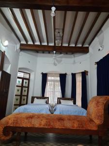 two beds in a room with a couch and a window at Heritage Home, Hampe's in Mysore