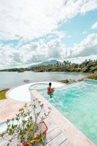 un hombre en una piscina al lado de un cuerpo de agua en Peninsula Esmeralda Luxury Villas, en San Felipe de Puerto Plata