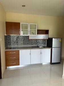 a kitchen with white cabinets and a white refrigerator at Prautamnak Grand Apartments in Pattaya South