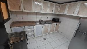 una pequeña cocina con fregadero y nevera. en Adbldna01, en Abu Dabi