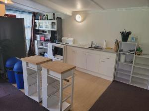 una cucina con armadietti bianchi ed elettrodomestici bianchi di Kai Iwi Lakes Resort a Kaihu