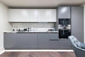 a white kitchen with white cabinets and an oven at Garden Haven Luxe 1BR 1BA Chigwell Retreat CHCL F1 in Chigwell +22 photos