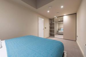 a bedroom with a blue bed and a mirror at Garden Haven Luxe 1BR 1BA Chigwell Retreat CHCL F1 in Chigwell