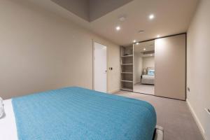a bedroom with a blue bed and a mirror at Garden Haven: Luxe 1BR 1BA Chigwell Retreat in Chigwell