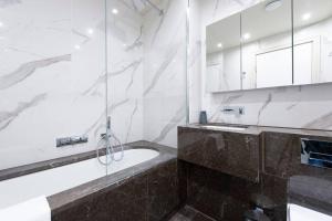 a bathroom with a tub and a glass shower at Garden Haven: Luxe 1BR 1BA Chigwell Retreat in Chigwell