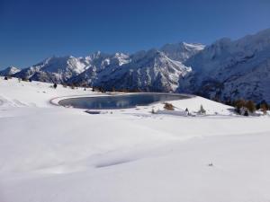 een meer in de sneeuw met bergen op de achtergrond bij CA' DEI MARIANE in Vermiglio
