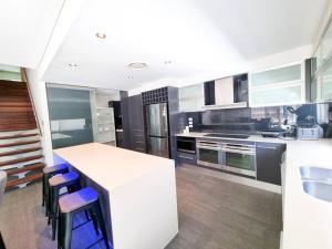 黄金海岸Stylish Surfers Paradise Haven 4BR4B Stunning Pool 2的厨房配有白色的柜台和蓝色的凳子