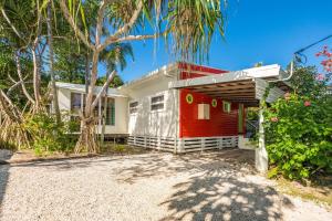 a red and white house with palm trees at A Perfect Stay - Beachcombers Cottage in Suffolk Park