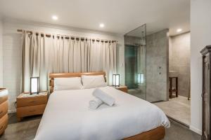 a bedroom with a large white bed and a shower at A Perfect Stay - Brandon St Beach and Spa in Suffolk Park