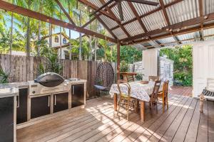 un patio al aire libre con mesa y parrilla en A Perfect Stay - Byron Surf Cottage, en Byron Bay