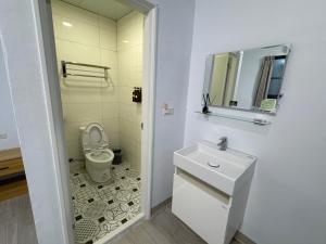 uma casa de banho com um WC, um lavatório e um espelho. em 茄萣路科民宿 