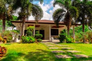 una casa con palme e un vialetto di PATIO BUENDIA FARM RESORT AND EVENTS PLACE a Amadeo