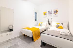 - 2 lits dans une chambre aux murs blancs dans l'établissement Estación RooMalaga by Bossh Apartments, à Malaga