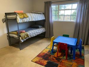 Bloemfontein的住宿－Le Petit Guesthouse，客房设有带桌椅的双层床。