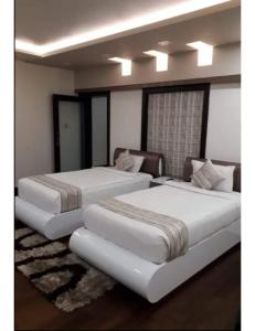 two white beds in a room with at Hotel Somraj Regency, Tripura in Agartala