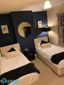 a bedroom with two beds with a mirror at Scenery Senary by Sheryl - Large house, Right in Town Centre, Near Northampton Gen Hospital in Northampton