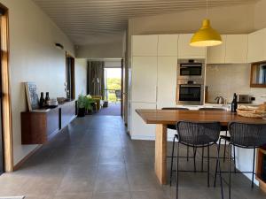 cocina con mesa de madera y sillas en La Bodega Waiheke Island, en Surfdale