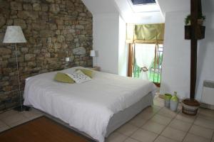 1 dormitorio con cama y pared de piedra en Ferme Saint Christophe, en Saint-Marcan