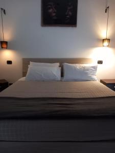 1 dormitorio con 1 cama con 2 almohadas y 2 luces en Il Brindisi di C & C Castelli Romani, en Pomezia