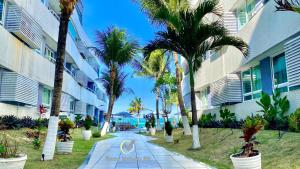 a walkway with palm trees in front of a building at Ponta Negra Beach beira-mar in Natal