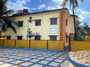 un bâtiment avec une clôture jaune devant lui dans l'établissement Shreesham Resort at Malpe Beach, à Udupi
