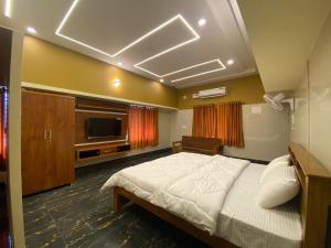 a bedroom with a bed and a flat screen tv at Shreesham Resort at Malpe Beach in Udupi