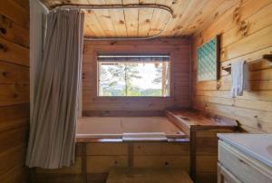 a bath tub in a wooden bathroom with a window at Adelaide's Den cabin in Townsend