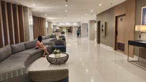 a woman sitting on a couch in a lobby at The New Villa at Sea Residences in Manila