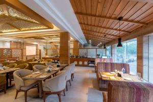 un restaurante con techos de madera, mesas y sillas en Spring Valley Resorts by DLS Hotels, en McLeod Ganj