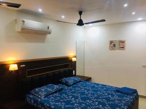 a bedroom with a bed with blue sheets and a ceiling fan at Vaishnavi furnished flats in Mangalore