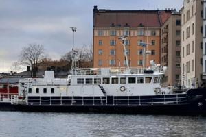 a boat docked in the water next to buildings at Hotellilaiva Muikku/Hotel Boat Muikku in Helsinki