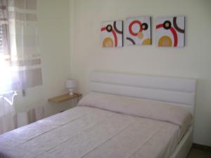 a white bedroom with a bed and two paintings on the wall at Torrebianca in Erice