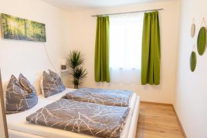2 camas en un dormitorio con cortinas verdes en Knollgut Ferienwohnung Buchberg, en Goldegg