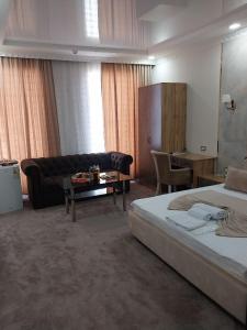 ein Hotelzimmer mit einem Bett, einem Sofa und einem Tisch in der Unterkunft Sharq hotel in Urganch