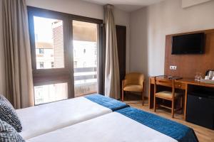 a hotel room with a bed and a desk and a window at Hotel Adonis Plaza in Santa Cruz de Tenerife