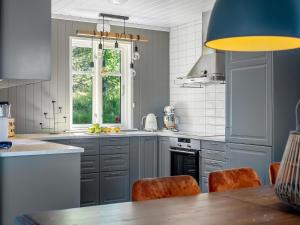 a kitchen with gray cabinets and a table with orange chairs at Villa Heidi · Mjøsa-utsikt · Jacuzzi Badstu · 30 min OSL in Ulven +19 photos