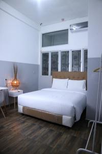 una camera da letto con un grande letto bianco e un tavolo di 360 Homestay Padang a Kampungdurian