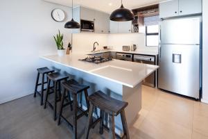 a kitchen with a large island with bar stools at The Tyne Luxury Apartments in Durban